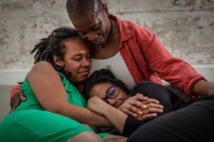 Three people share a close, comforting embrace