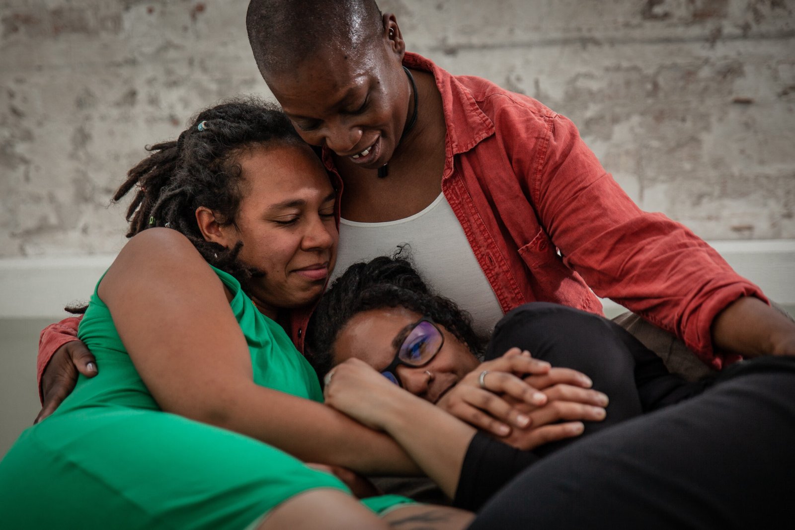 Three people share a close, comforting embrace