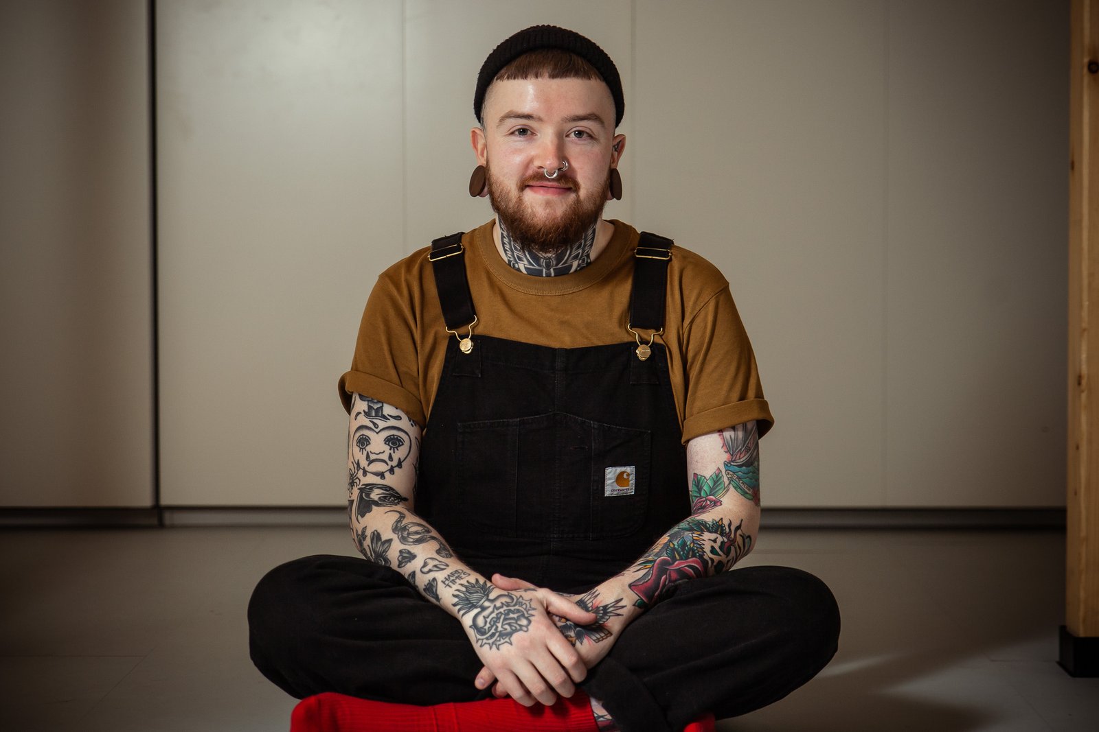 mg 8933 Tattooed man in overalls sitting cross-legged indoors