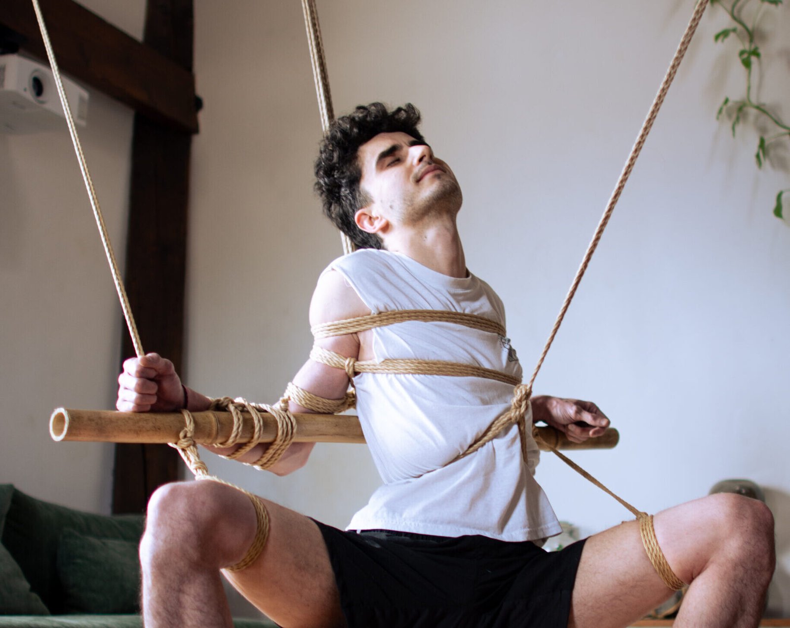 predicaments Man bound with ropes on suspended wooden bar